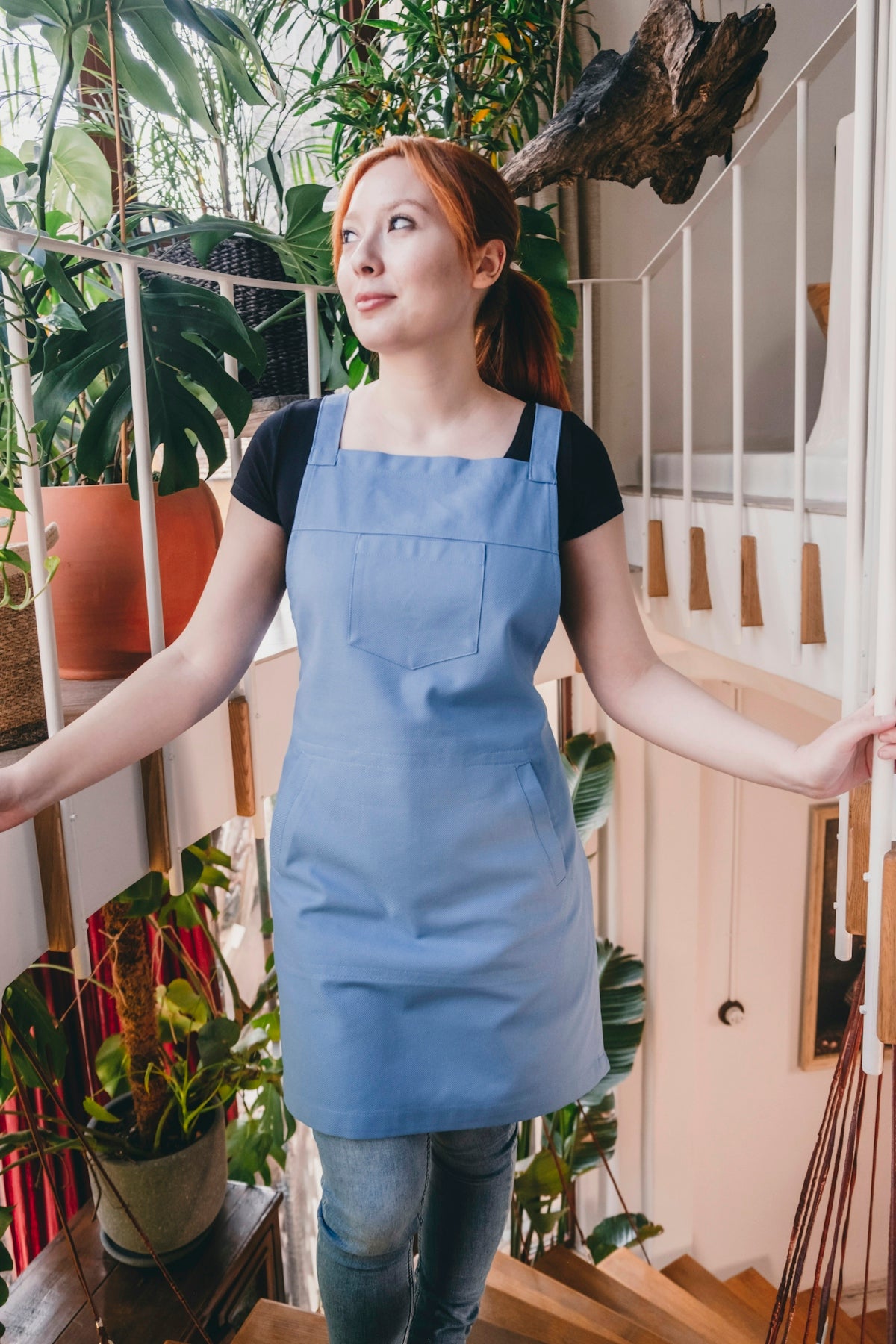 A woman in a blue apron is standing on the stairs